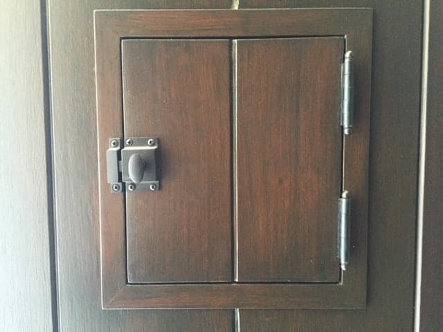 Mahogany speakeasy hatch with dark metal latch and hinges
