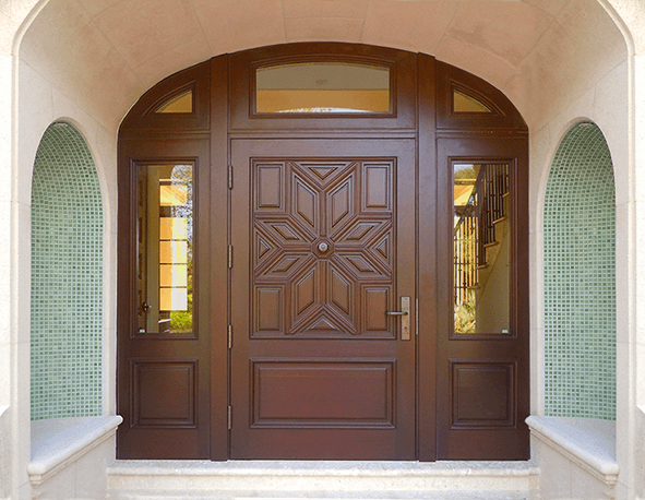 Arched mahogany entry door with carved star panel and mosaic tile niches
