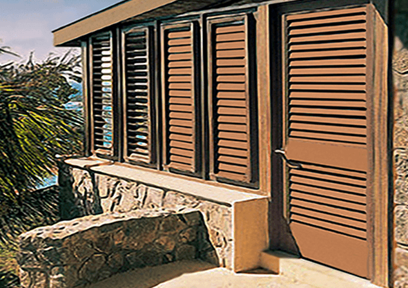 Louvered mahogany shutters and door on a stone coastal building